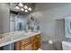Bathroom featuring tile countertops, wooden cabinetry, decorative mirrors, and modern light fixture at 1127 Buttermilk Rd, Larkspur, CO 80118