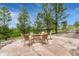 Inviting stone fire pit on a large patio with natural landscaping and seating, perfect for outdoor entertaining at 1127 Buttermilk Rd, Larkspur, CO 80118