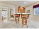 Kitchenette featuring wood cabinetry, granite countertops, barstool seating, and an adjacent bathroom at 1127 Buttermilk Rd, Larkspur, CO 80118