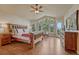 Light-filled main bedroom with vaulted ceiling, wood floors, and views of nature at 1127 Buttermilk Rd, Larkspur, CO 80118