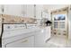 Well-lit laundry room with floral wallpaper features white cabinets, washer, dryer, and window at 6023 E Briarwood Dr, Centennial, CO 80112