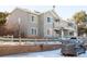 Corner view of a gray two story townhome exterior with patios, brick accents, and a gray fence in a snowy landscape at 912 S Yampa St # 206, Aurora, CO 80017