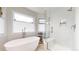 Bright bathroom features a soaking tub under a window and tiled shower with seating and recessed shelving at 10886 Pheasant Run, Littleton, CO 80125