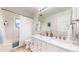Well-lit bathroom with double sinks, white cabinetry, and tub shower at 10886 Pheasant Run, Littleton, CO 80125