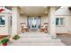 Covered front porch features white brick, two rocking chairs, a frosted glass front door, and manicured lawn at 10886 Pheasant Run, Littleton, CO 80125