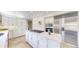 Spacious kitchen island with a cooktop, white cabinetry, and stainless steel refrigerator at 10886 Pheasant Run, Littleton, CO 80125