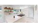 Bright kitchen with white cabinets, marble countertops, floating shelves, and a center island cooktop at 10886 Pheasant Run, Littleton, CO 80125