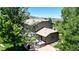 Home's rear exterior with lush yard, mature trees, and a patio featuring a hot tub at 10886 Pheasant Run, Littleton, CO 80125