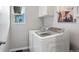 Well-equipped laundry room features modern washer and dryer units, overhead cabinets, and a bright window at 1788 Alpine Dr, Erie, CO 80516
