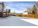 Snowy backyard featuring a wooden deck, surrounded by a tall wooden fence and glimpses of neighboring homes at 16651 E Arizona Pl, Aurora, CO 80017