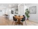 Bright dining area featuring a wood table, sleek black chairs, and modern lighting, open to a gourmet kitchen at 9976 E 63Rd Ave, Denver, CO 80238