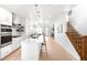Bright, open-concept living space with a modern kitchen, dining area, and staircase at 9976 E 63Rd Ave, Denver, CO 80238