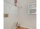 Bright laundry room with white walls, wooden floors, and a wire rack shelf for storage at 5160 Hannibal St, Denver, CO 80239