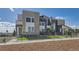 Modern townhome featuring stone accents, neutral siding, landscaped front yard, and metal perimeter fencing at 6880 Bryant Way, Denver, CO 80221