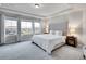 Spacious bedroom featuring a tufted headboard, tray ceilings, and expansive windows with neighborhood views at 7012 S Undergrove Way, Aurora, CO 80016