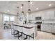 Modern kitchen featuring a granite countertop island with seating and white cabinets, illuminated by pendant lights at 7012 S Undergrove Way, Aurora, CO 80016