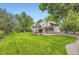 Large backyard with mature trees, lush green grass, deck and a covered patio at 5475 W Ottawa Ave, Littleton, CO 80128