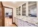 White butler's pantry featuring glass cabinets and contrasting dark hardware and countertops at 5475 W Ottawa Ave, Littleton, CO 80128
