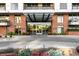 Stunning brick building entrance featuring a modern glass awning and manicured landscaping at 333 S Monroe St # 211, Denver, CO 80209