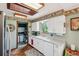 Well-lit kitchen featuring white cabinets, a garden window, and an adjacent laundry room at 8840 Niwot Rd, Niwot, CO 80503