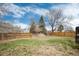 Fenced backyard with trees, grass and view of the neighborhood from the edge of the deck at 1296 Ascot Ave, Highlands Ranch, CO 80126