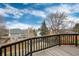 View from a wooden deck of other homes with fenced yards set against a scenic backdrop of trees and a cloudy sky at 1296 Ascot Ave, Highlands Ranch, CO 80126