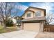 Tan two-story home with a two-car garage and well-manicured lawn at 1296 Ascot Ave, Highlands Ranch, CO 80126