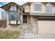 Inviting front entrance with covered porch, stone accents, and two-car garage at 1296 Ascot Ave, Highlands Ranch, CO 80126