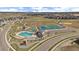 Overhead shot of the community amenities including pool, sport courts, parking, and playground with neighborhood and open space views at 14268 Hop Clover Trl, Parker, CO 80134