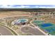 Aerial view of a community pool with playground, sports courts, ample parking, and new housing construction in the background at 14268 Hop Clover Trl, Parker, CO 80134
