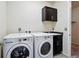 Bright laundry room with a washer, dryer, dark cabinets, and a view into another room at 7426 E 148Th Pl, Thornton, CO 80602