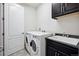 Well-lit laundry room featuring a utility sink, washer, dryer, and dark wood cabinets at 7426 E 148Th Pl, Thornton, CO 80602