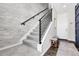 Modern staircase with grey carpet, white risers, and black metal railing adjacent to light grey brick accent wall at 3560 Corsica Way, Castle Rock, CO 80109