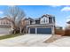 Two-story blue home featuring a three-car garage, stone accents, and a well-maintained front yard at 10606 Cottoneaster Way, Parker, CO 80134