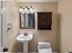 Small powder room featuring a pedestal sink, toilet, and wall cabinet at 10606 Cottoneaster Way, Parker, CO 80134