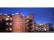 Brick apartment building with multiple levels and balconies at dusk at 800 W Belleview Ave # 407, Englewood, CO 80110