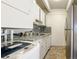 Galley kitchen with gray tile, white cabinets and a sink at 800 W Belleview Ave # 407, Englewood, CO 80110