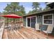 Spacious wooden deck with red umbrella, patio seating, and sliding glass door offers an ideal entertainment area at 94 Spring Ln, Boulder, CO 80302