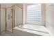 Bathroom featuring a glass enclosed shower, soaking tub and a glass block window at 5204 Shetland Ct, Highlands Ranch, CO 80130