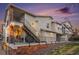 Exterior view of a modern townhouse featuring a private patio, stairs, and brick foundation at sunset at 1646 S Deframe St # B8, Lakewood, CO 80228