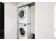 Efficient laundry closet with stacked washer and dryer, plus built-in shelving for storage at 8122 E 6Th Pl, Denver, CO 80230