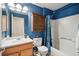 Blue bathroom featuring a shower-tub combo, wooden cabinet, and toilet at 5556 Lewiston Ct, Denver, CO 80239