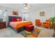 Bright main bedroom featuring a ceiling fan, carpet, colorful art, a gray bed frame and orange bedding at 5556 Lewiston Ct, Denver, CO 80239