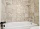 Bright bathroom featuring a clean white bathtub with tan stone-look tiling and corner shelves at 3225 S Garrison St # 19, Lakewood, CO 80227