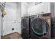 Well-equipped laundry room with modern washer and dryer units, white cabinets, and tiled flooring at 317 Bonanza Dr, Erie, CO 80516