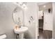 Powder room with a pedestal sink, oval mirror, decorative wall texture and adjacent staircase at 77 N Jackson Gap Way, Aurora, CO 80018