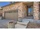 Close-up of home's stone facade, two-car garage, decorative planters, and front entrance at 77 N Jackson Gap Way, Aurora, CO 80018