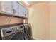 Modern laundry room features front loading washer and dryer, gray cabinets and ample storage space at 77 N Jackson Gap Way, Aurora, CO 80018