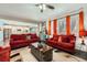 Bright living room with hardwood floors, windows with orange curtains, and an open view of the kitchen at 77 N Jackson Gap Way, Aurora, CO 80018