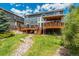 Exterior rear of the home with multi-level deck, lush green lawn, stone feature, and mature trees at 19105 Eagle Ridge Dr, Golden, CO 80401